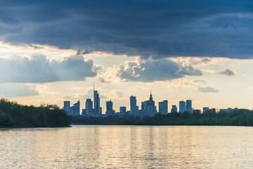 Sunny cloudy day big city of Warsaw skyline in spring, high skyscrapers over Wisla river surface....