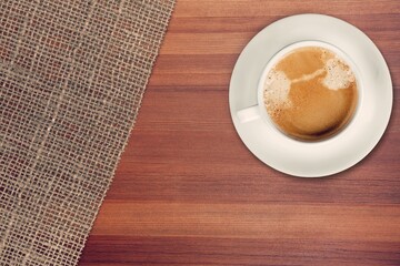 White Cup of Coffee on Wooden desk with burlap napkins