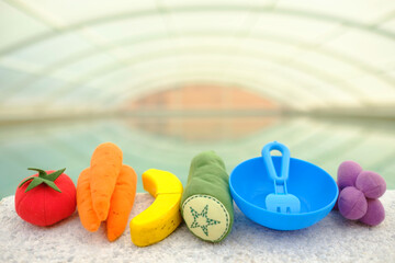 fruits of toys with the colors of the LGTBIQ+ collective flag on the edge of a swimming pool.