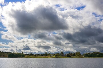 A river landscape in the countryside with large gray clouds in dramatic backlighting. Waiting for a coming thunderstorm