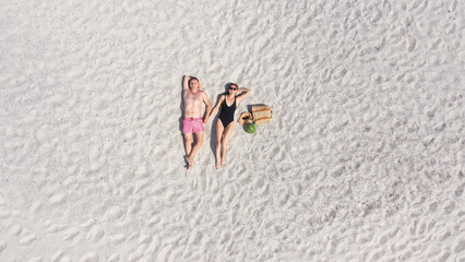 Fototapeta na wymiar Aerial view of a young couple lying on the white sand. man and woman spend time together and travel through the desert.