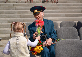 PYATIGORSK, RUSSIA - MAY 09, 2011: Girl gives flowers to veteran on Victory Day. - obrazy, fototapety, plakaty