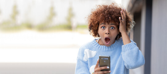 girl with mobile phone in the street and expression of surprise