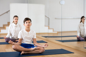 Teen boy exercising with sister, mother and father at yoga class, friendly family practicing self-care