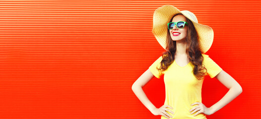 Summer portrait of beautiful happy smiling woman wearing yellow straw hat and dress on red background