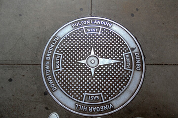 Brooklyn manhole, beneath Brooklyn bridge with cardinal star directions. 