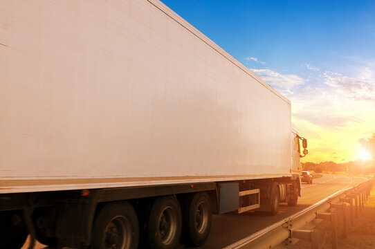 Close-up of the big truck with a trailer on a countryside road against a sky with a sunset
