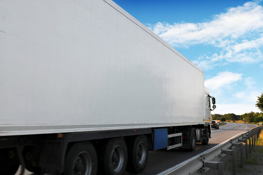 Close-up of the big truck with a trailer on a countryside road against a sky with clouds