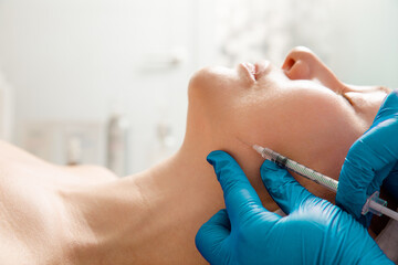 Cosmetologist performs the chin lift procedure by injecting beauty injections. Doctor injecting...