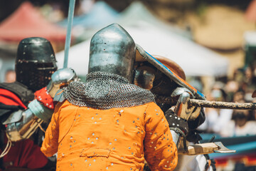 Pitch battle of medieval knights, using metal armor, axes, swords and shields to defend themselves.