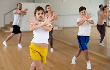 Fototapeta na wymiar Young girl exercising aerobic dance with her family in gym.