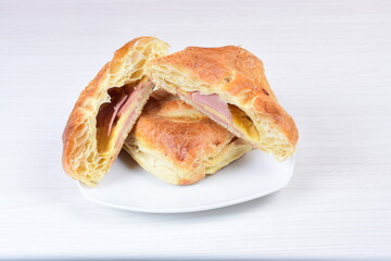 Ham and cheese puff pastry, accompanied by corn sauce on a wooden background