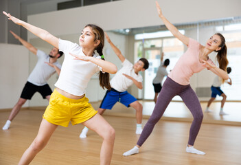 Plakat Happy sporty family of four enjoying active dance in modern studio. Focus on smiling brunette teenage girl..