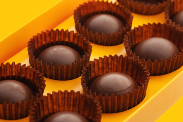 handmade chocolates with honey filling in a yellow box isolated on a white background