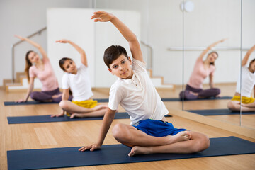 Teen boy exercising with sister, mother and father at yoga class, friendly family practicing self-care