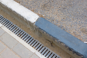square curbstone and drainage grate by the road