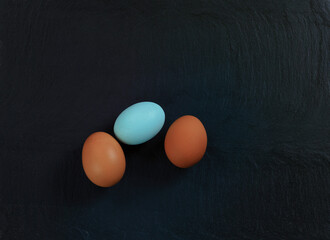 Three chicken eggs on slate stone