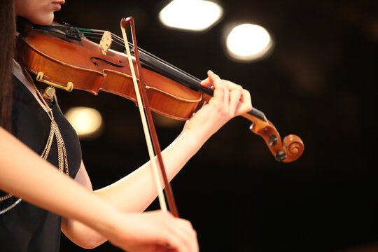 A musician playing a musical instrument violin isolated on black illuminated by a white spotlight