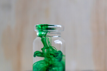 pequeña botella de vidrio con tinta comestible color verde diluida en agua