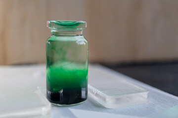 pequeña botella de vidrio con tinta comestible color verde diluida en agua