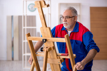Old male carpenter repairing drawing easel