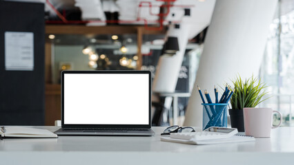 Fototapeta Mockup laptop computer with white screen put on desk table of business office. obraz