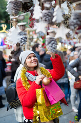 Happy girl chooses Christmas toys on the street market. High quality photo