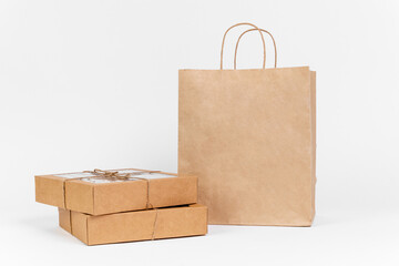 Two boxes of recyclable cardboard are tied with twine and stand next to a craft paper bag, ready for delivery. Packaging of goods for an online store, copy space, studio shooting
