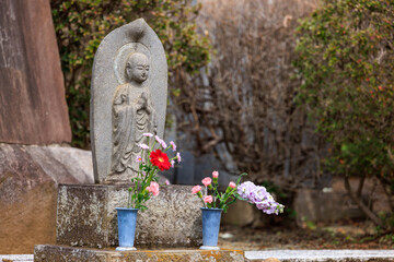 地蔵の形をした墓に手向けられた花