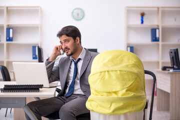 Young male employee looking after new born at workplace