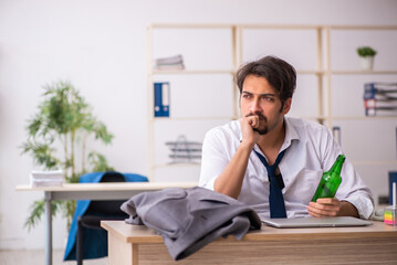 Young alcohol addicted employee sitting in the office