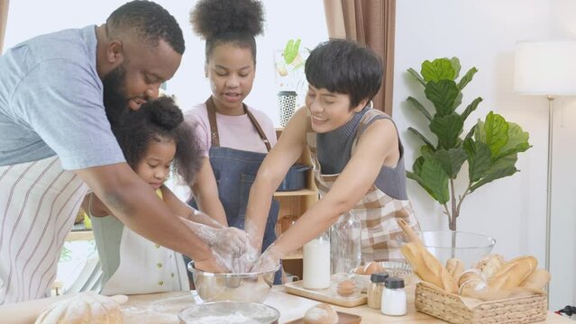 African America family wearing apron thresh flour for cooking bakery or bread together in the kitchen at home, parent and little child preparing food with fun and playful, relationship and activity.