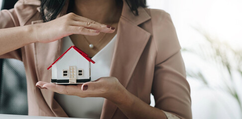 Close up of businesswoman holding model house. Architecture, building, construction, real estate and property concept