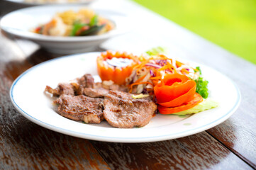 Grilled steaks and vegetables.Beef steak on white plate with vegetables and sauce isolated on wooden  background.Photo select focus.