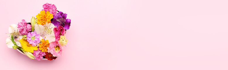 Heart made of beautiful different flowers on light pink background with space for text