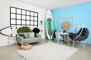 Interior of modern room with comfortable workplace and board for sup surfing near color wall