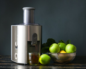 New modern juicer and glass of fresh juice with apples on dark wooden table
