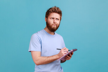 Portrait of bearded man making notes in paper notebook, writing business idea, future plans,...
