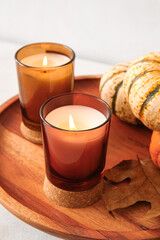 Wooden stand with burning candles and pumpkins on table, closeup