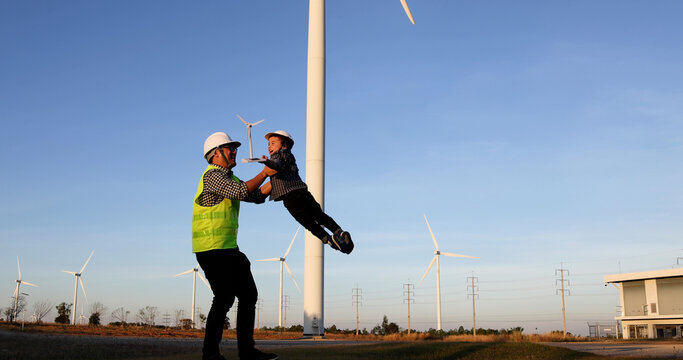Asian engineer father with his son in the wind turbines farm, Family with environmental engineering renewable energy concept
