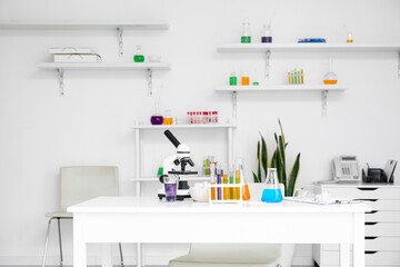 Microscope and chemical glassware on table in medical laboratory