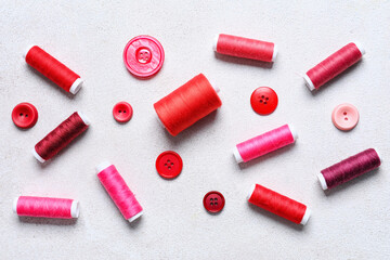 Sewing threads and buttons on light background