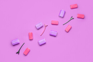 Hair curlers and clips on color background
