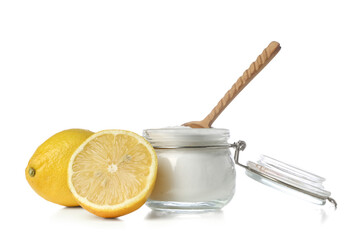 Jar of baking soda and ripe lemons on white background