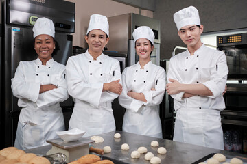 A Group of multiracial professional happy chefs team staff in white cooking uniforms stands in a...