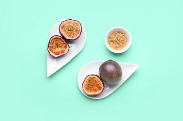 Plates with delicious passion fruits and bowl with pulp on green background