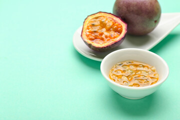Plate with delicious passion fruits and bowl with pulp on green background
