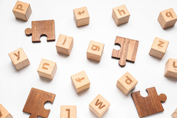 Wooden cubes with letters and puzzle pieces on white background