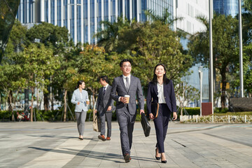 young asian businesspeople walking on street