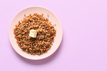 Plate of tasty buckwheat porridge on pink background